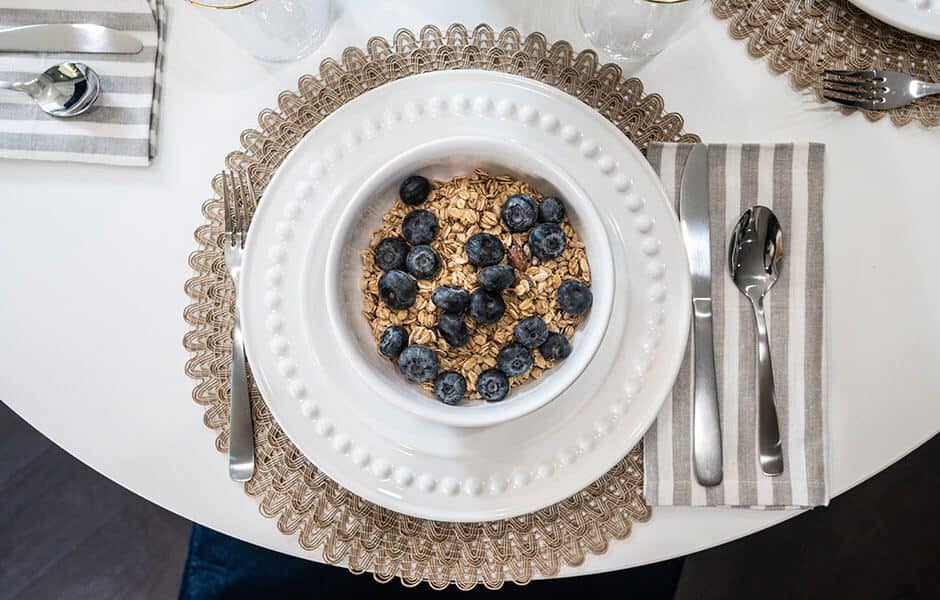 Bowl of granola with blueberries on a set dining table