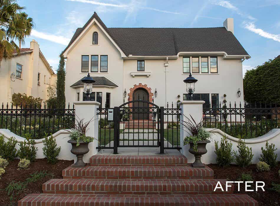 An after image of a renovated two-story home with a gated brick entrance, manicured landscaping, and elegant exterior details