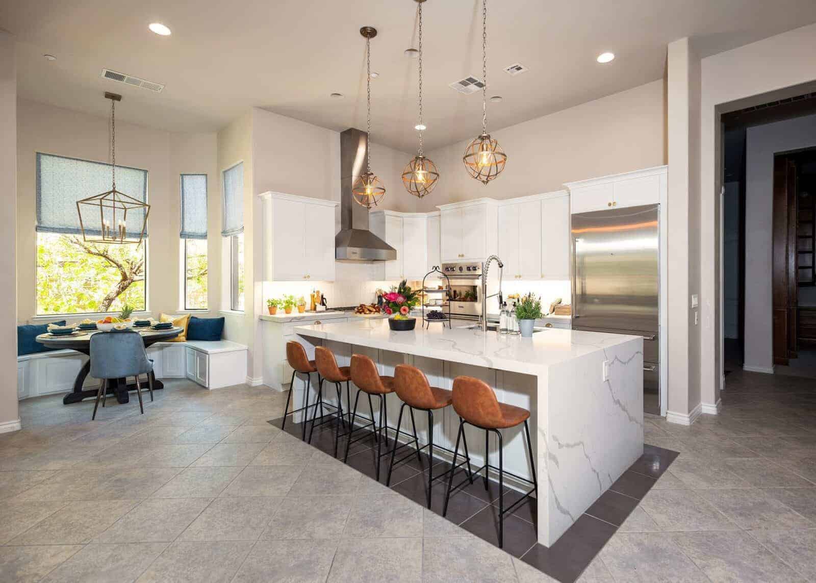 Spacious kitchen with white cabinets, a large island with a white marble countertop, and a breakfast nook