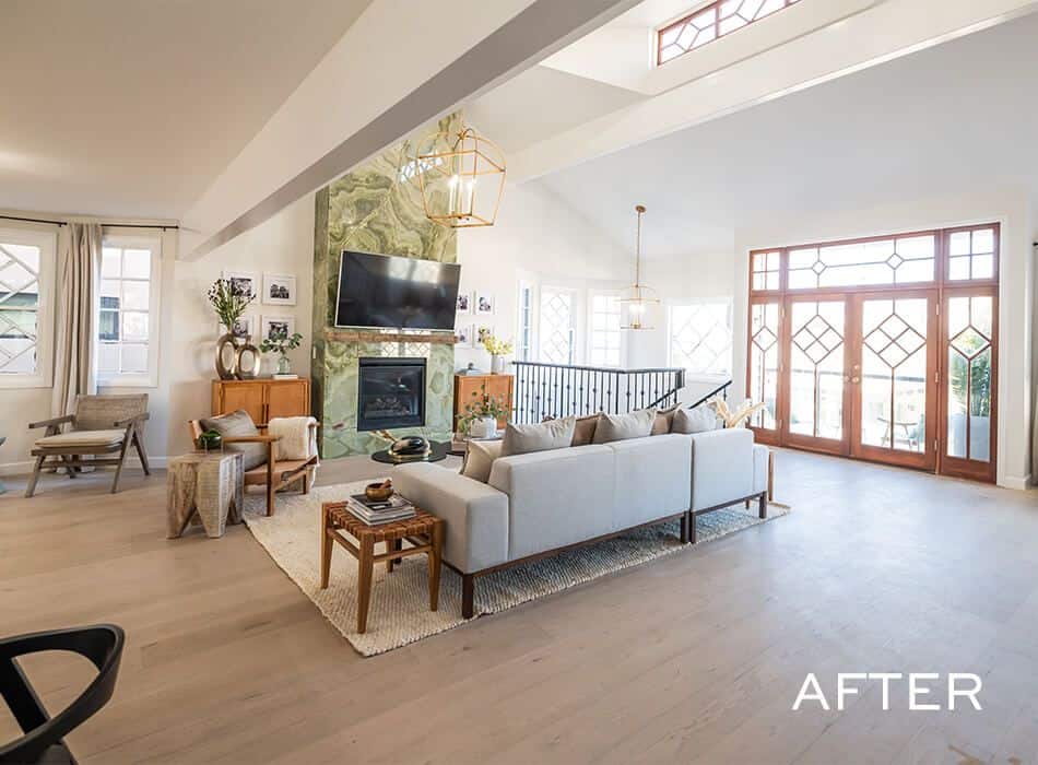 Living room with a vaulted ceiling, a green marble fireplace, a large TV, and a gray sectional sofa