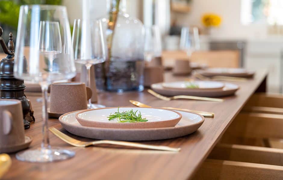 Elegant table setting with ceramic dishes, gold cutlery, and rosemary sprigs