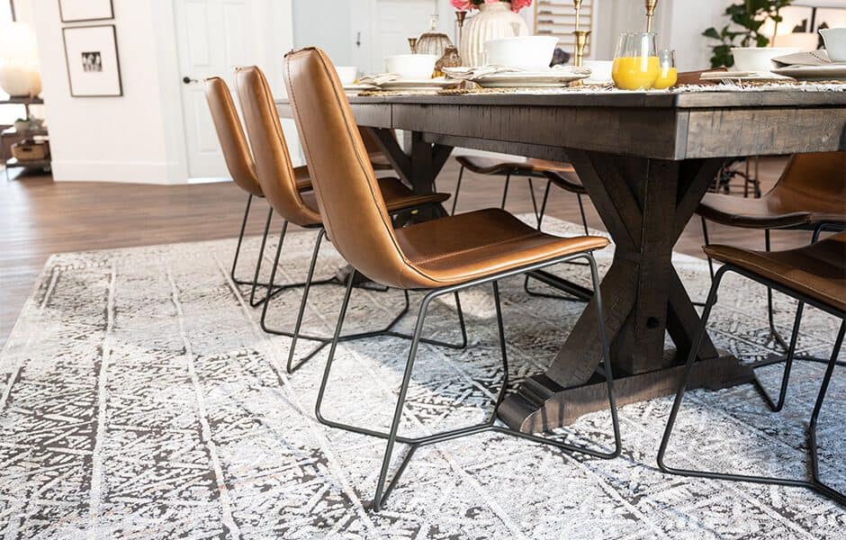 Dining room with leather chairs and a rustic wooden table on a patterned rug