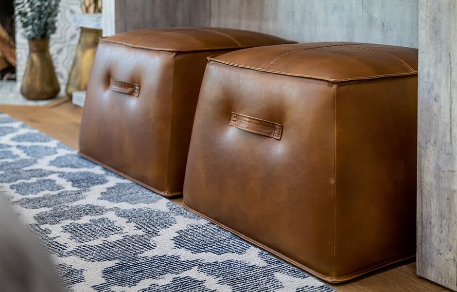 Two brown leather ottomans placed on a patterned rug