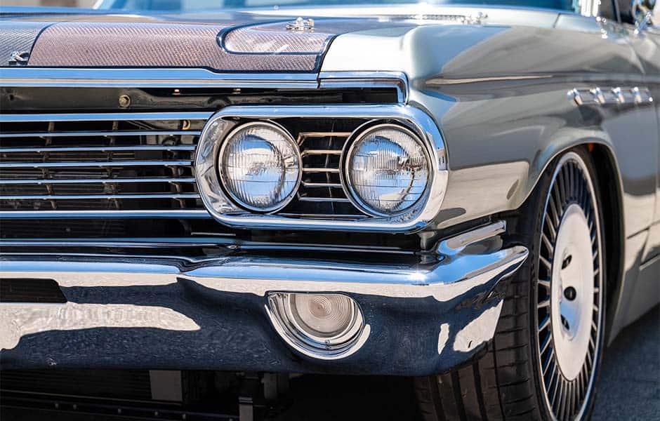 Close-up of a vintage car's chrome grille, headlights, and front bumper with detailed styling