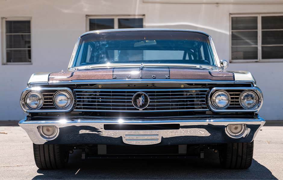 Classic vintage car with chrome detailing and a polished front grille in a sunny outdoor setting
