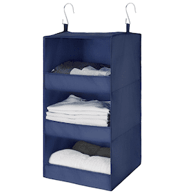 Navy blue hanging closet organizer with three shelves storing folded clothes