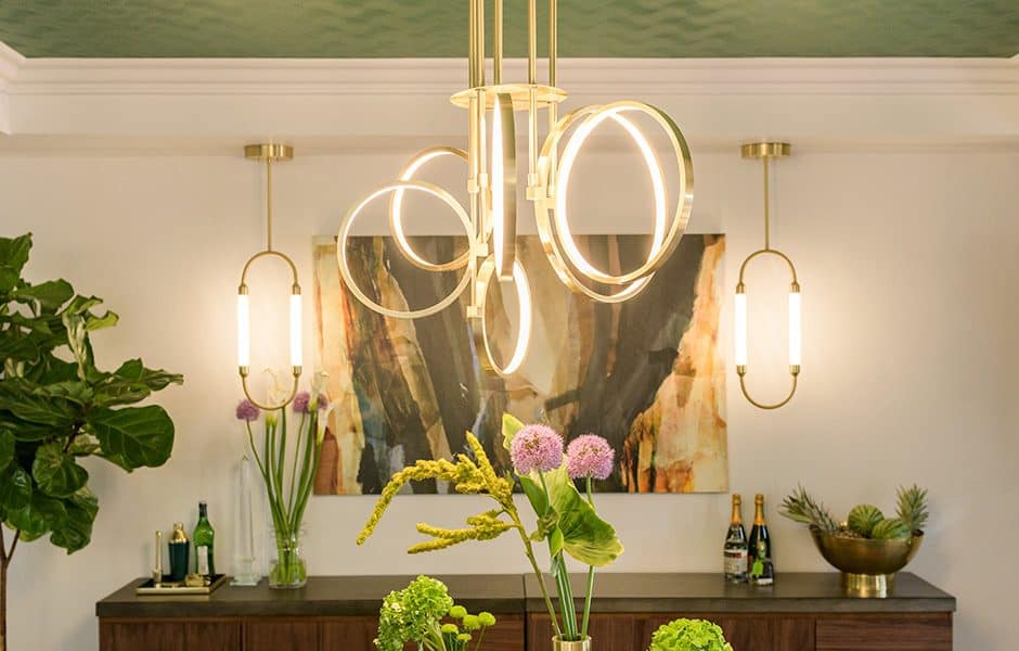 Modern dining room with a gold geometric chandelier, wall sconces, and a large abstract painting
