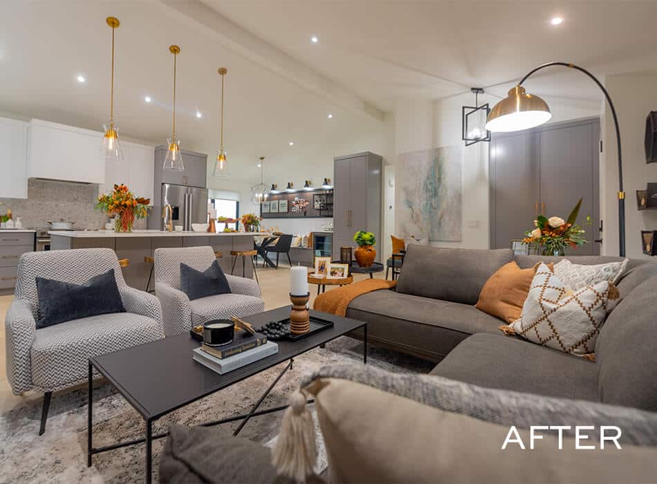 Modern open-concept living room with gray seating, a sleek kitchen, and warm decorative accents