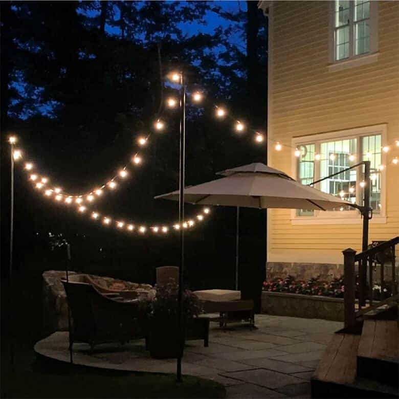 Backyard patio at night with string lights, umbrella, and outdoor seating