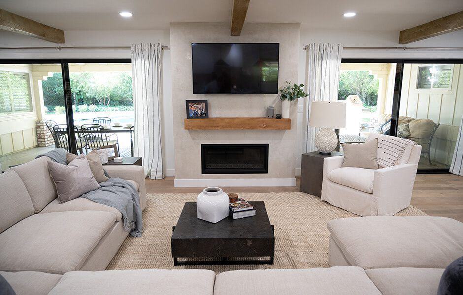 Modern living room with TV, fireplace, sofas, and doors to outside