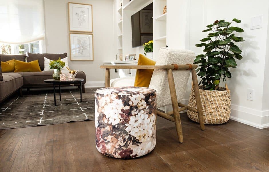 Cozy living space with floral ottoman, wooden chair, and vibrant decor accents