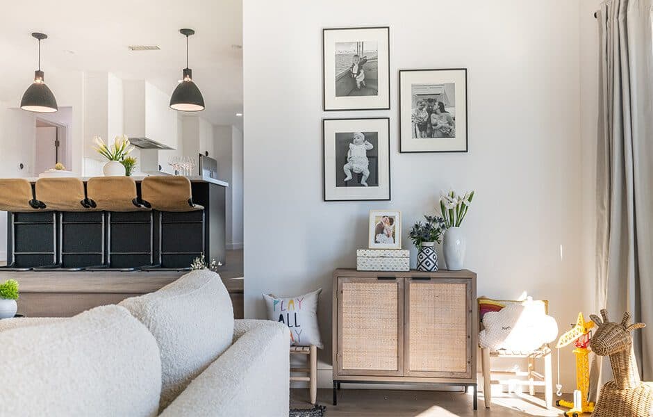 Living area with a light-colored sofa, wall art, a cabinet with decorative items, and a play area with toys