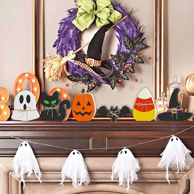 Halloween mantle with ghost garland, pumpkins, and witch-themed decor