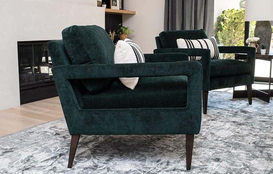 Green velvet armchairs with striped pillows in a modern living space
