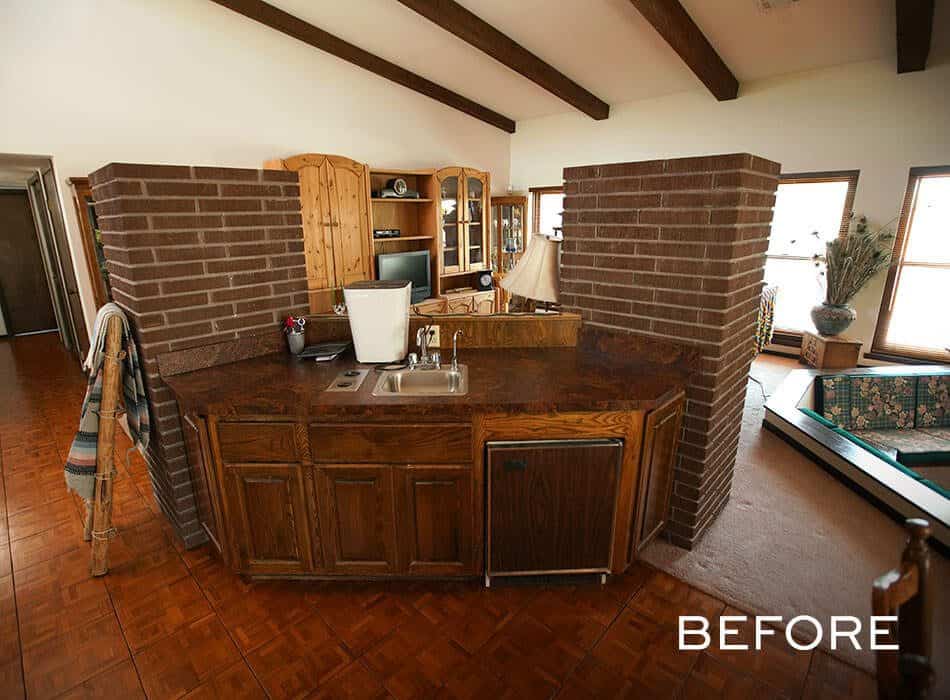 Dated bar area with dark wood cabinets, brick columns, and a compact sink setup