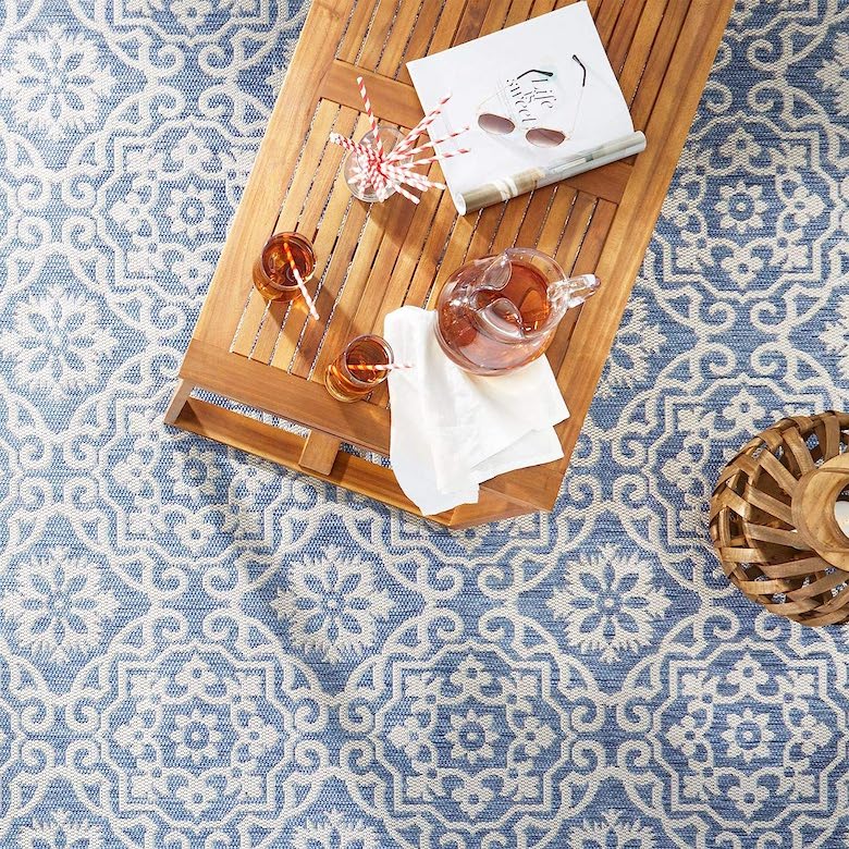Wooden tray with drinks, napkins, and a magazine on a blue and white patterned rug