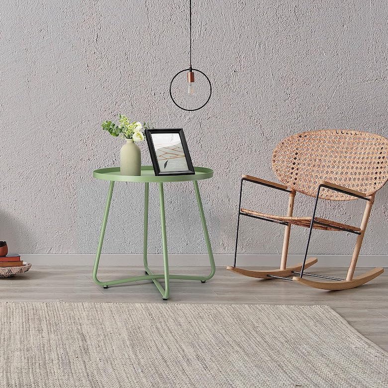 Living room with a green side table, framed photo, vase with flowers, and a woven rocking chair