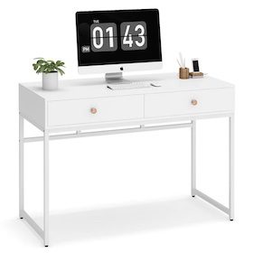 White desk with two drawers, a potted plant, and a computer monitor displaying a clock