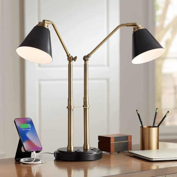 Brass and black adjustable desk lamp on a wooden workspace with office essentials