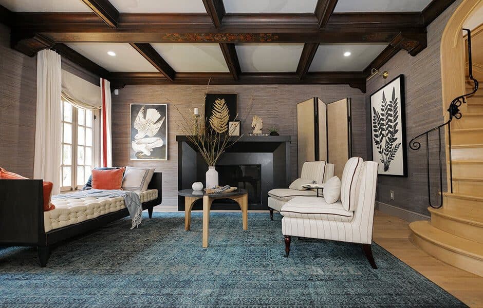 Living room with blue rug, striped chairs, daybed, and black fireplace