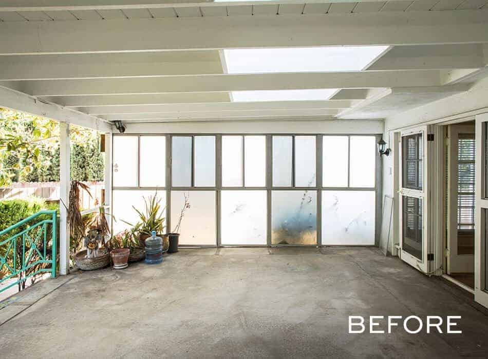 Covered patio with frosted glass panels, potted plants, and concrete flooring