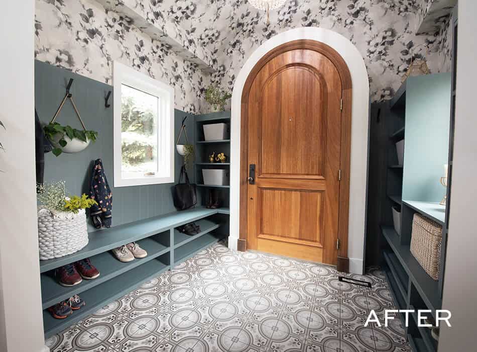 An after image of a modern entryway with patterned tile flooring, built-in teal storage, a wooden arched door, and floral wallpaper