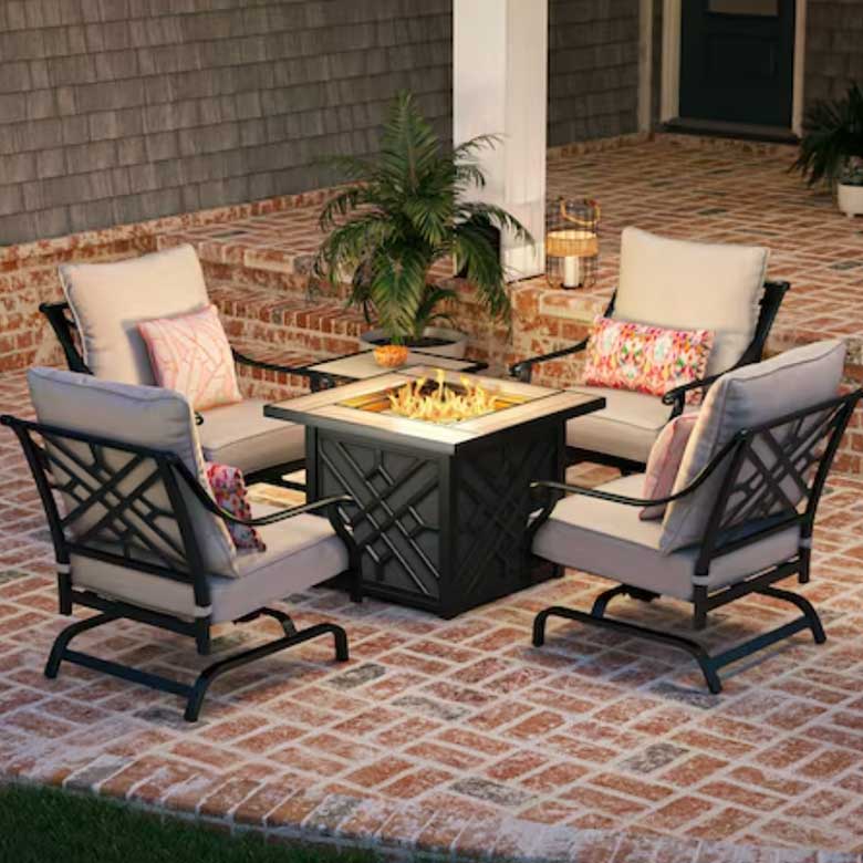 Outdoor seating area with four chairs around a fire pit on a brick patio
