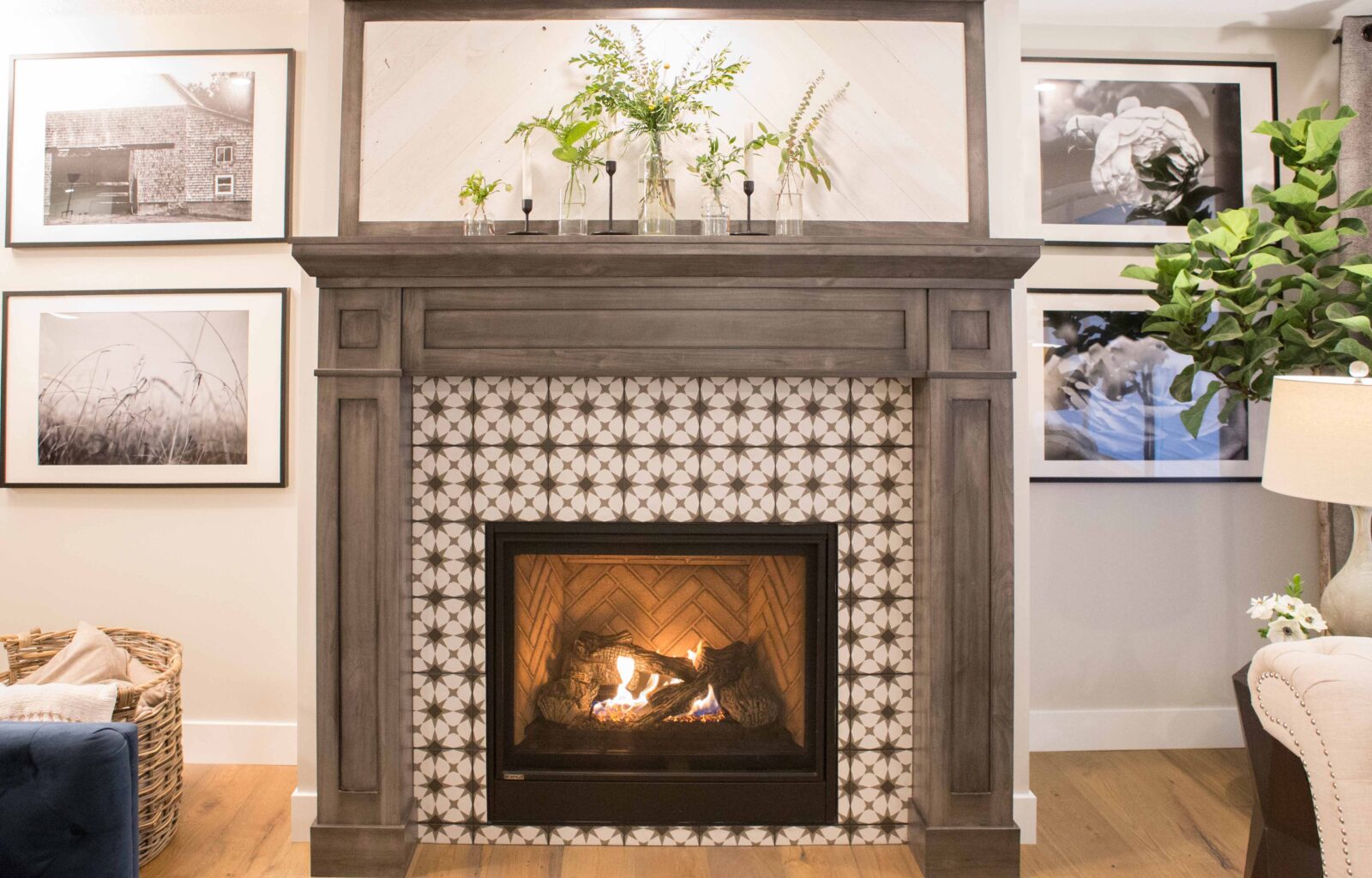 Decorative fireplace with patterned tile surround, wood mantel, and greenery in glass vases