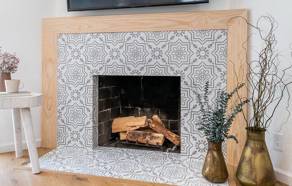 Modern fireplace with tiled surround, wooden mantel, vases, and table