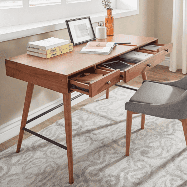 Wooden desk with open drawers, books, and a gray chair