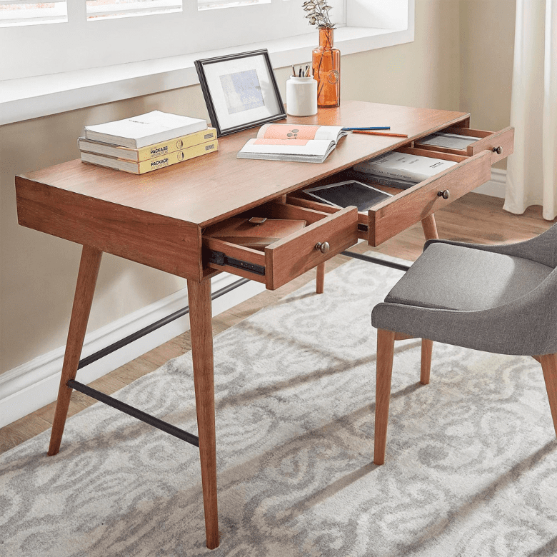 Wooden desk with open drawers, books, and a gray chair