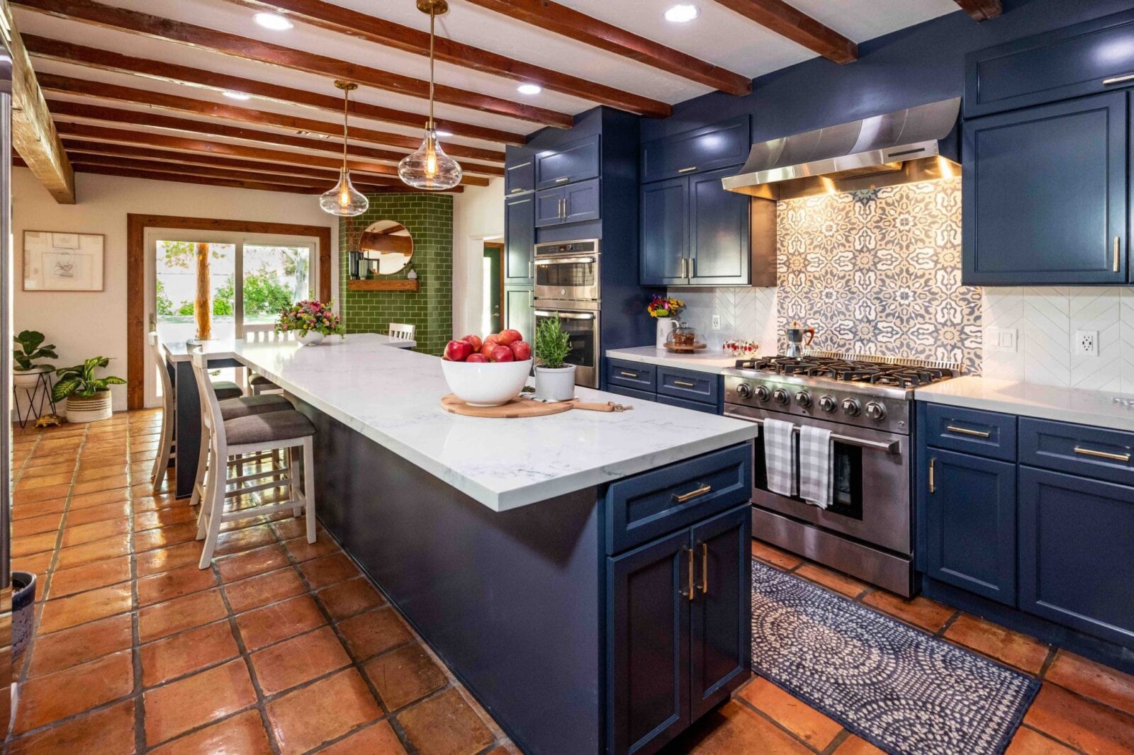 Kitchen with navy cabinets, white counters, patterned backsplash, island seating, and wood beams