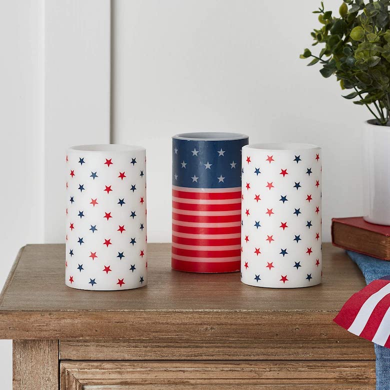 Patriotic candles with red, white, and blue star and stripe designs displayed on a wooden table