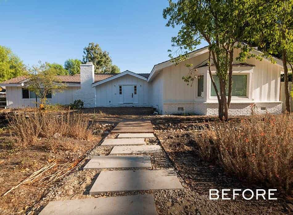 White ranch-style house with a dry, patchy front yard and stone walkway