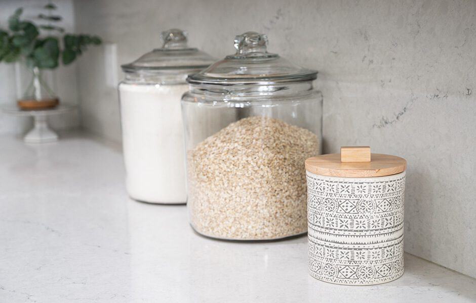 Three kitchen jars, one filled with rice, the other with flour, and a decorative canister with a wooden lid