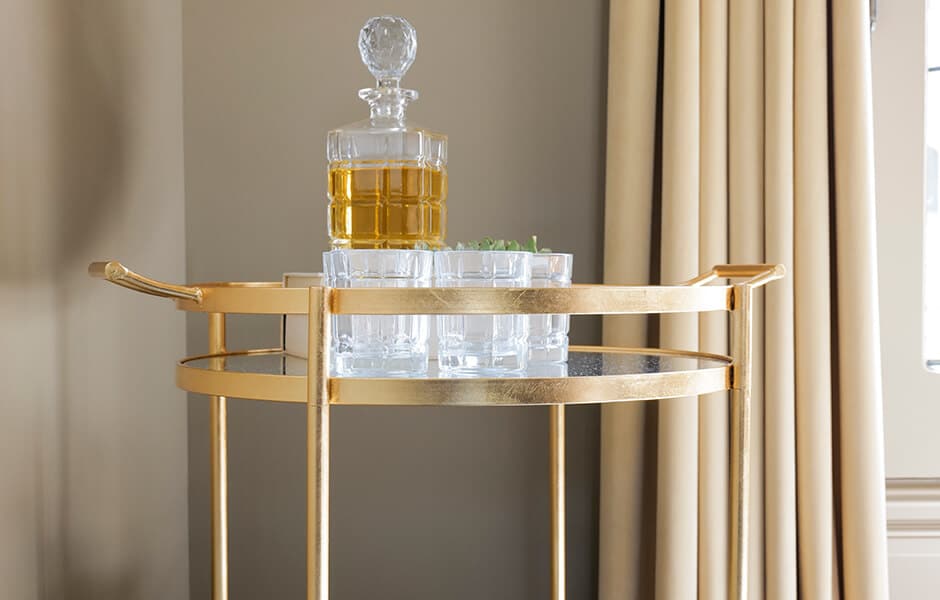 Gold bar cart with decanter and shot glasses