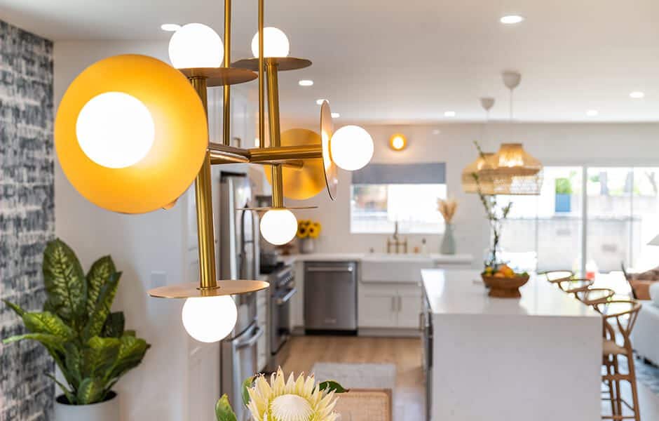 Modern kitchen with gold and glass chandelier white countertops and natural decor