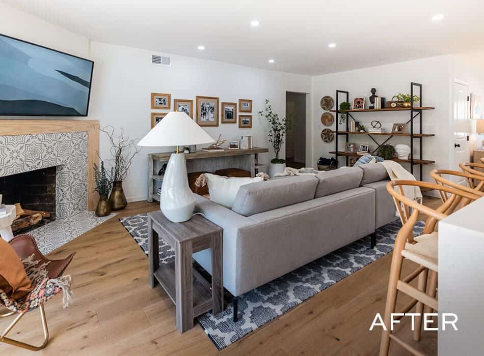 Living room with a gray sectional sofa, a tiled fireplace, wooden shelving, and a wall-mounted TV