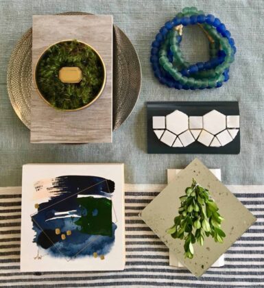Flat lay of greenery, beads, abstract art, and tiles on a textured surface