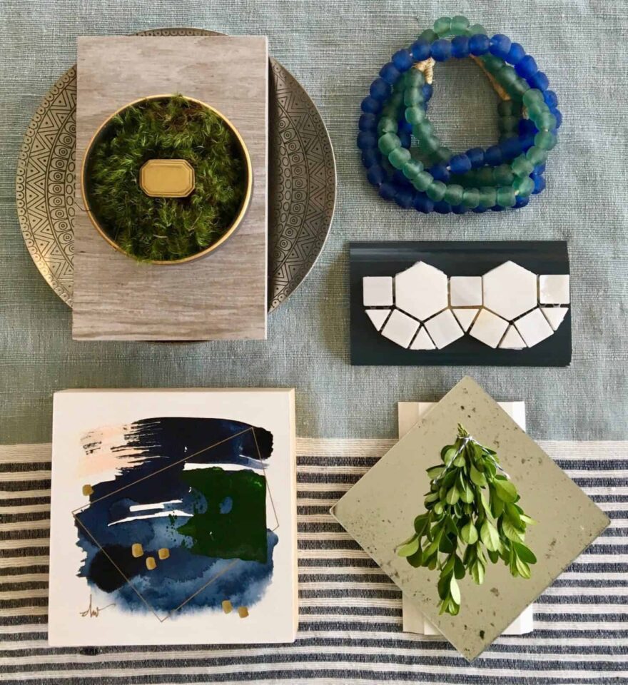 Flat lay of greenery, beads, abstract art, and tiles on a textured surface