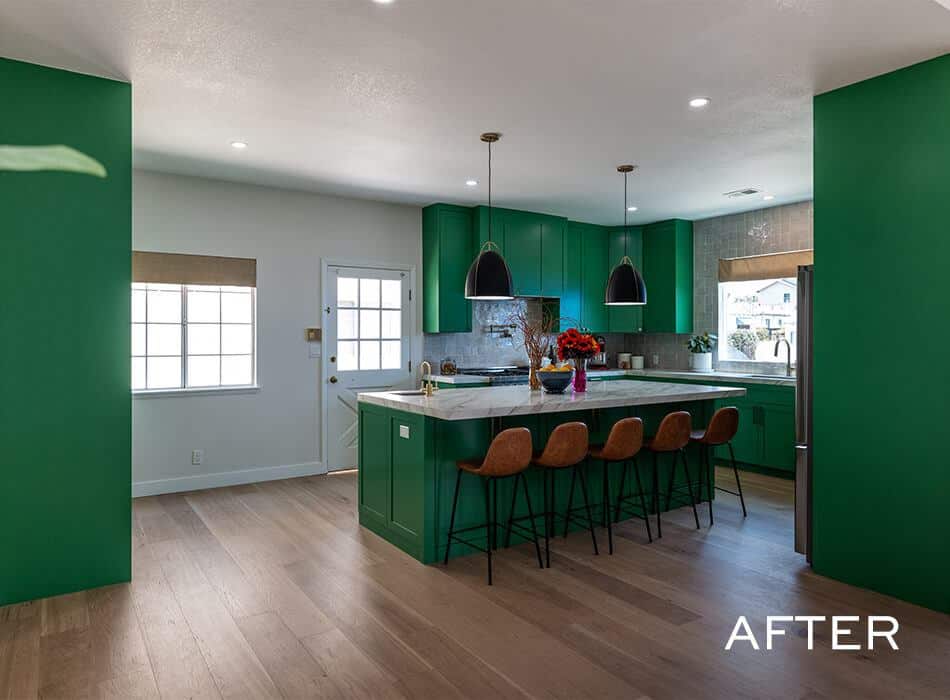 Modern kitchen with bold green cabinets, large island with bar stools, pendant lights, and wood flooring
