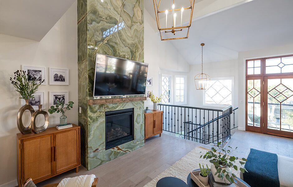 Living room with a green marble fireplace, mounted TV, and large windows