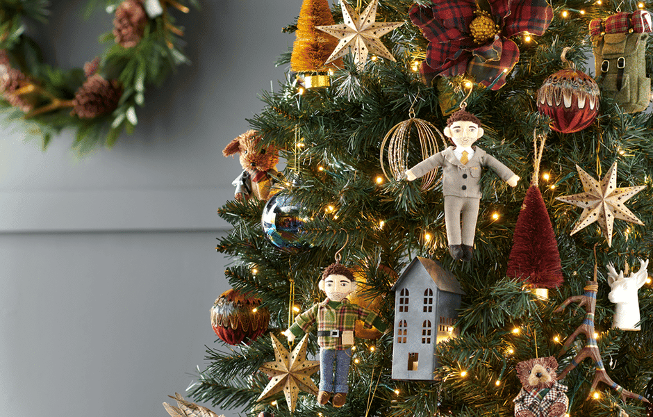 Christmas tree with lights, doll ornaments, stars, and festive decorations.