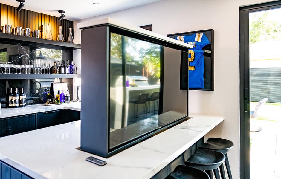 A modern kitchen with a built-in motorized television that rises from the countertop