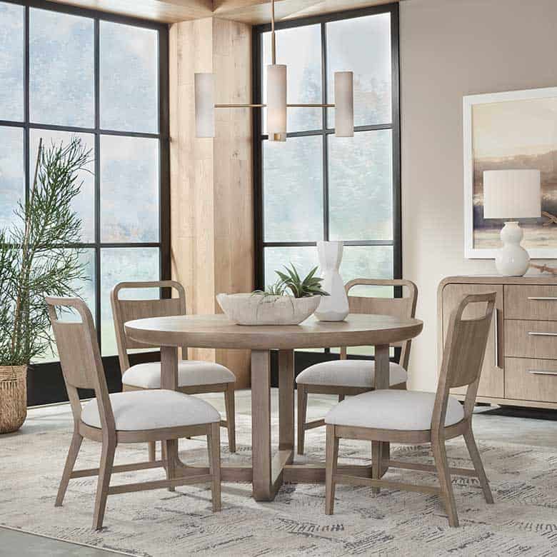 Dining room with round table, chairs, and large windows