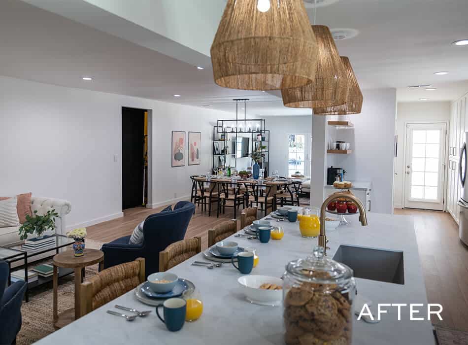 Modern kitchen and dining room with white cabinets, quartz countertop, wooden table, chairs, and unique changeliers