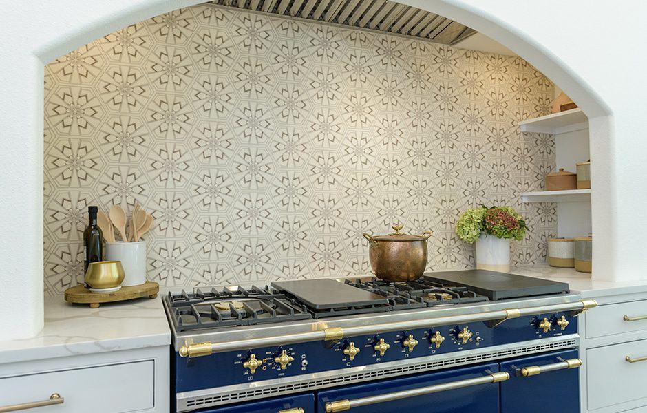 Modern kitchen with a blue gas range, white cabinets, a white marble countertop, and a patterned tiled backsplash