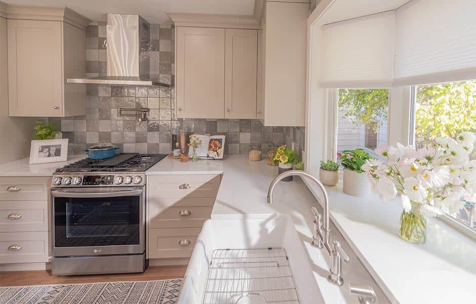 Kitchen with white cabinets, stainless steel range, farmhouse sink, tiled backsplash, window with curtains, and potted plants