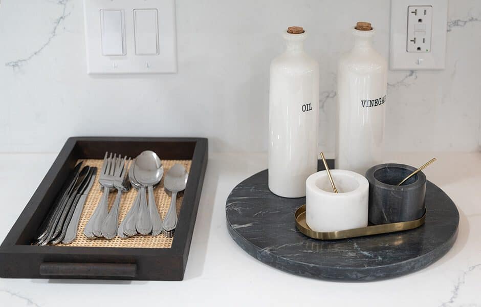 Kitchen countertop with silverware, oil and vinegar bottles, and marble cellars