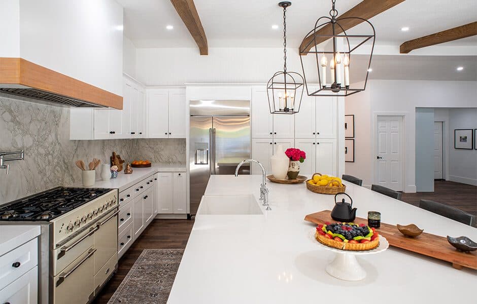 Modern kitchen with white island, cabinetry, marble backsplash, pendant lights, and decorative accents